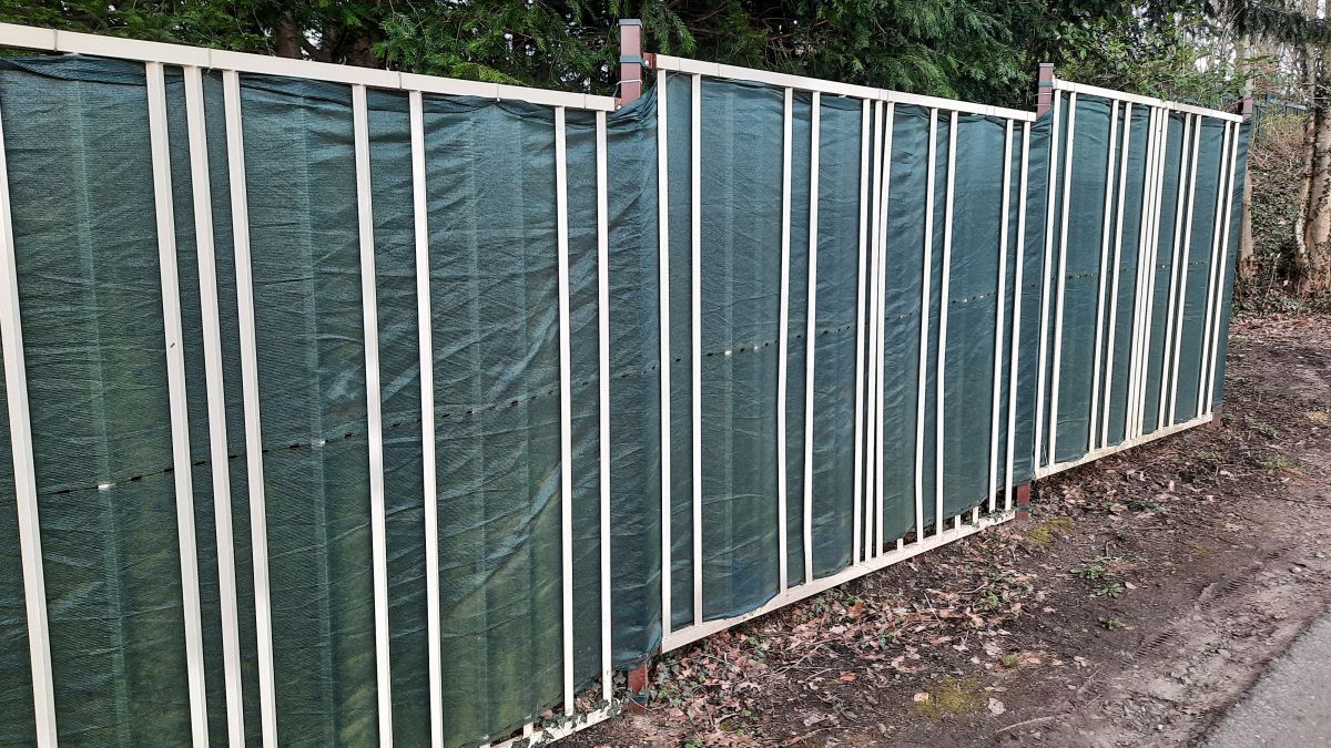 Zaunblende am stabilen Metallzaun, geflochten verspannt mit Kabelbindern