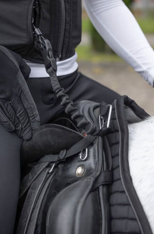 Die Airbag-Weste Manege wird über die Verbindungsleine am Sattel befestigt und kann bei einer Trennung vom Pferd ausgelöst werden